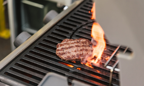A close up of a burger on a propane grill