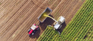An arial view of a tractor harvesting a crop field 