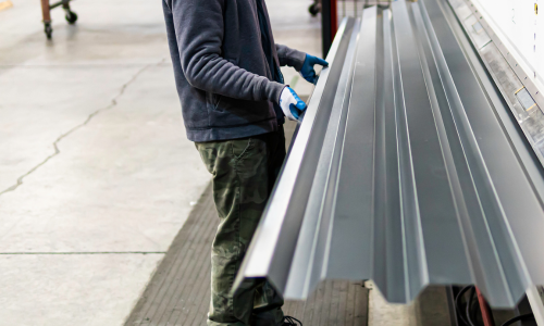 Metal siding being shaped and crimped by a machine
